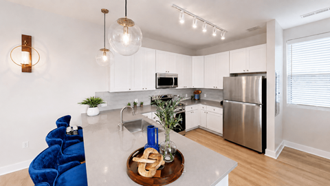 A modern kitchen with a blue chair and stainless steel appliances.