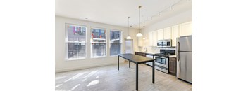 A kitchen with a table and chairs in front of a window with blinds.