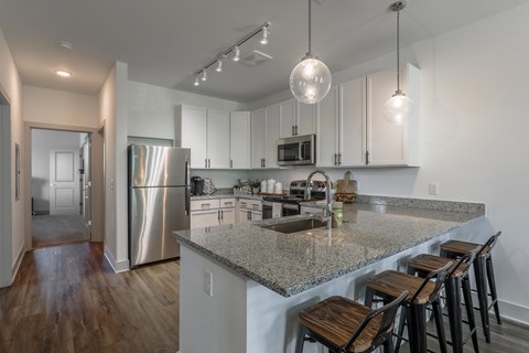 A kitchen with a granite countertop and stainless steel appliances.