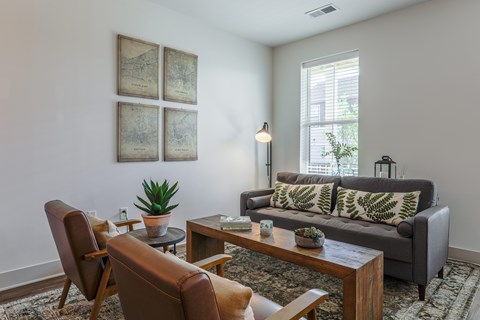 A living room with a grey couch, brown chairs, and a coffee table.