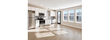 A modern kitchen with wooden floors and stainless steel appliances.