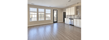 A spacious kitchen with white cabinets and a wooden floor.