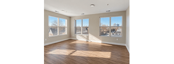 A large empty room with wooden floors and windows.