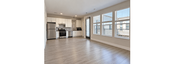 A spacious kitchen with stainless steel appliances and wooden flooring.