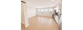 A kitchen with a refrigerator, cabinets, and a window overlooking a cityscape.