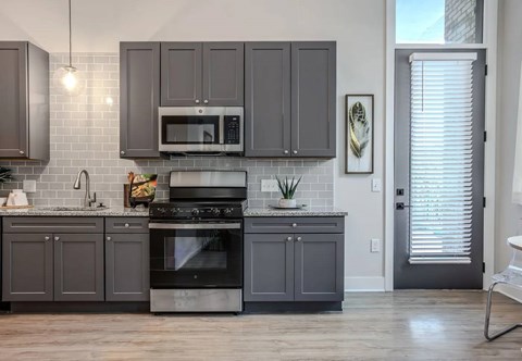 A kitchen with a black oven and grey cabinets.