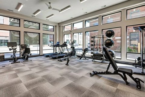 A spacious gym with a variety of equipment and large windows.