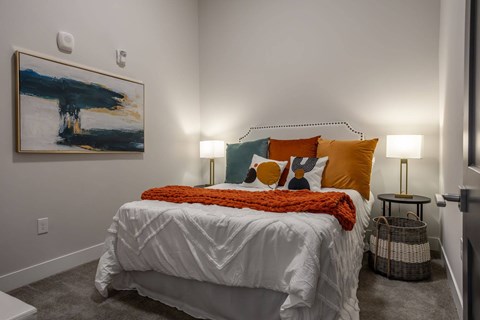 A bedroom with a white bed and a painting on the wall.