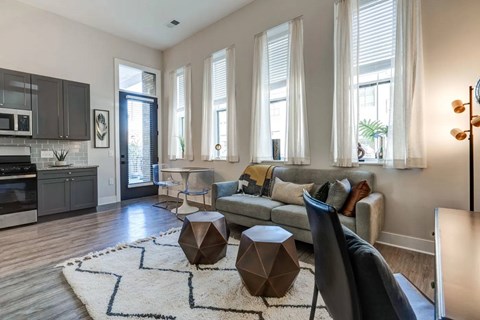 A modern living room with a grey sofa, a wooden coffee table, and a rug with a geometric design.