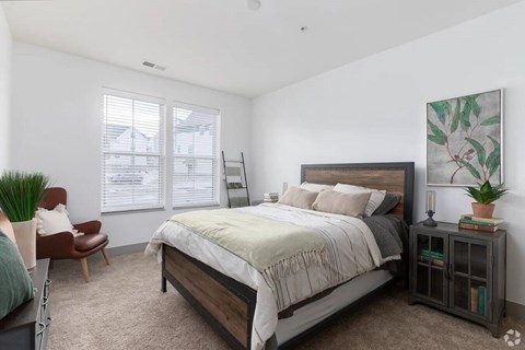A bedroom with a bed, chair, and a painting on the wall.