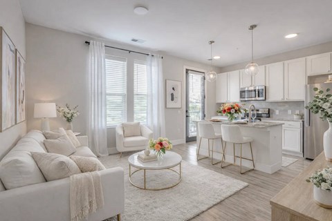 A modern living room with a white sofa, a coffee table, and a kitchen area in the background.