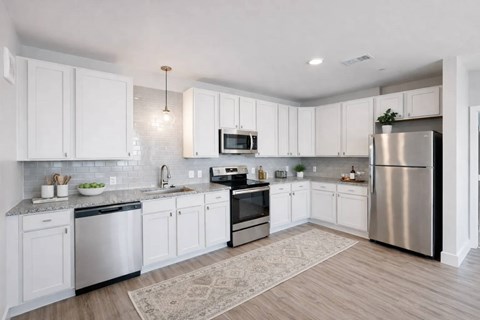 A modern kitchen with white cabinets and stainless steel appliances.