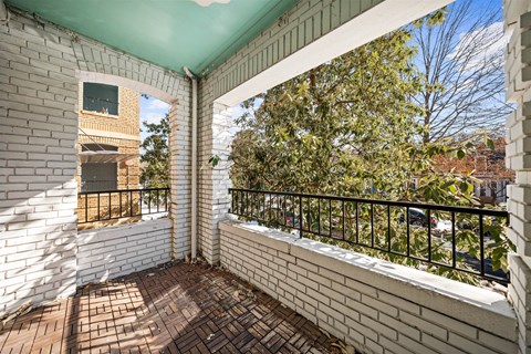A balcony with a brick floor and a green awning.