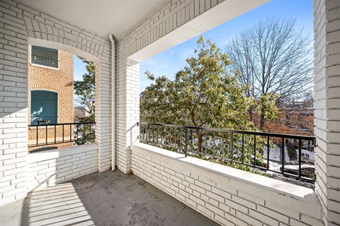 A balcony with white brick walls and a black railing.