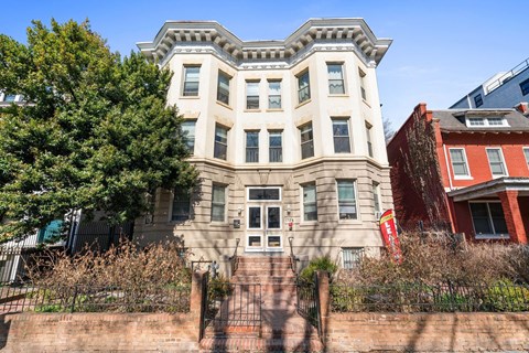 A large, old building with a red brick wall in front.