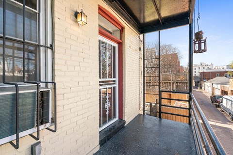 A balcony with a red door and a black railing.