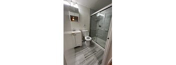 A bathroom with a toilet, sink, and shower.
