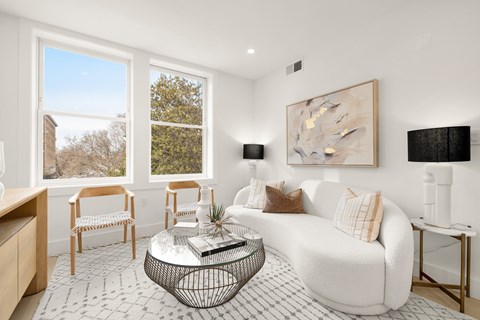 A living room with a white couch, a coffee table, and a painting on the wall.