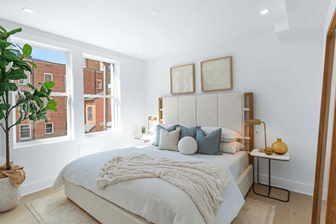 A bedroom with a large bed and a potted plant.