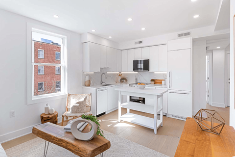 A modern kitchen with white cabinets and a wooden coffee table.