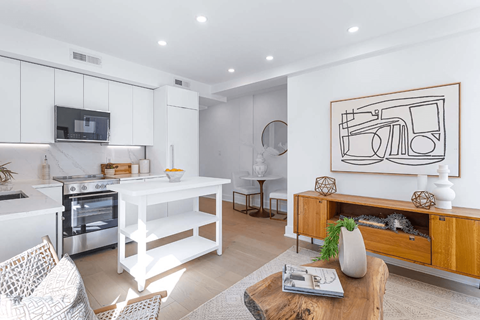 A modern kitchen with a white color scheme and a large painting on the wall.