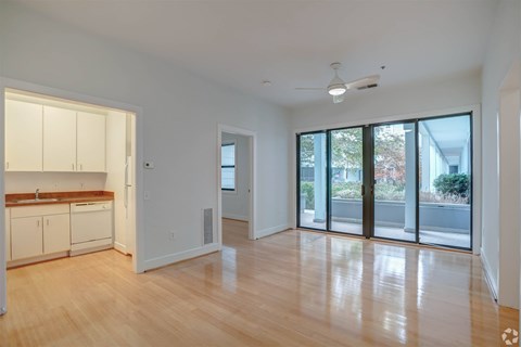A spacious room with wooden floors and a ceiling fan.