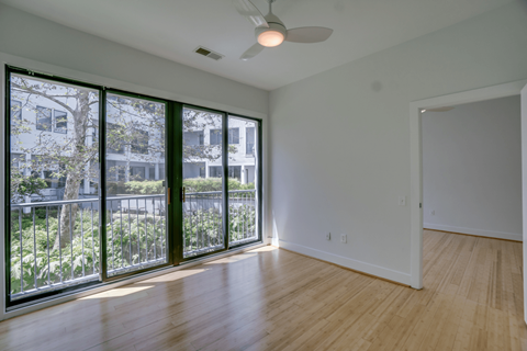 A room with a ceiling fan and a view of a building outside.
