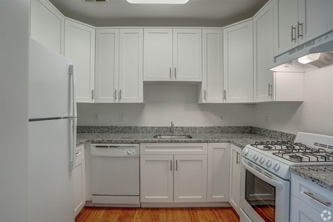 A kitchen with white cabinets and a white stove top oven.