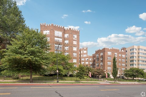 A large brick building with a green tree in front of it.