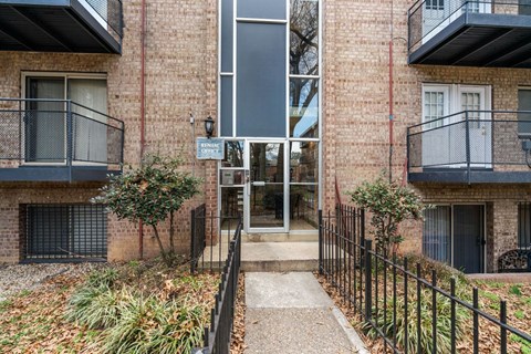 The image shows a building entrance with a black gate and a sign that reads "ENTRANCE".