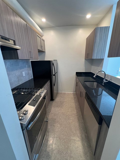 A kitchen with black countertops and stainless steel appliances.
