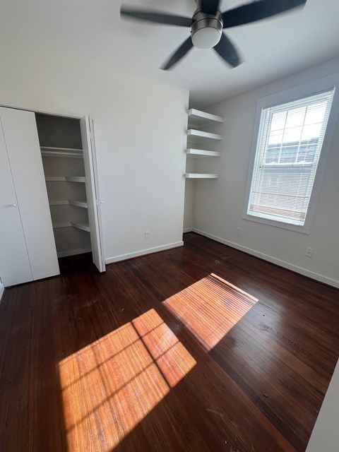 A room with a ceiling fan and wooden floors.