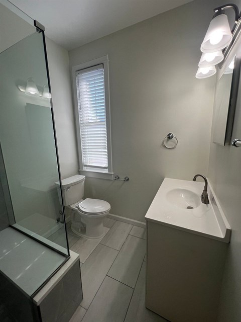 A white sink is in a white bathroom with a toilet and a shower.