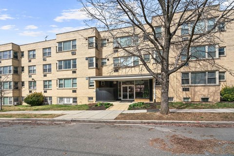 A large apartment building with a tree in front.