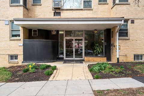 A brick building with a black awning and glass doors.