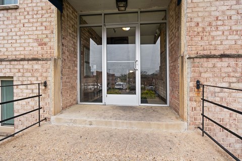 A glass door is at the end of a concrete walkway.