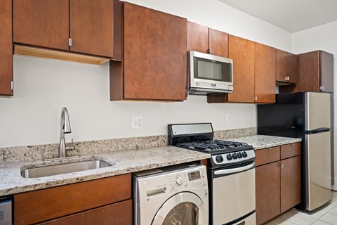 A kitchen with brown cabinets and a black refrigerator.