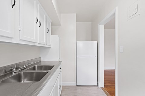 A kitchen with white cabinets and a white refrigerator.