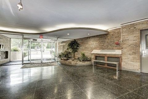 A spacious lobby with a stone floor and a brick wall.