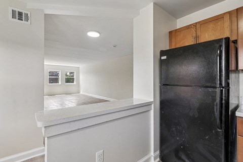 A black refrigerator in a kitchen with white walls.