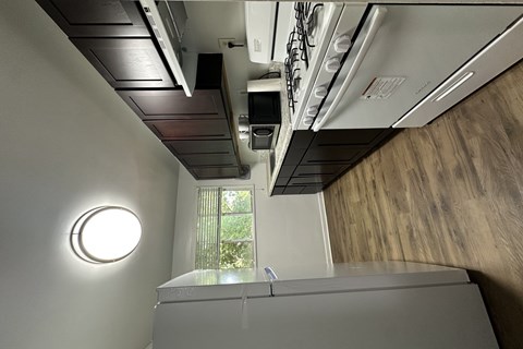 A modern kitchen with a stainless steel oven and a round light fixture on the wall.