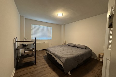 A bedroom with a bed, desk, and chair.