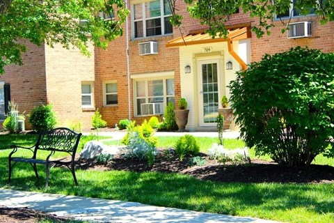 A black bench is in front of a brick building.