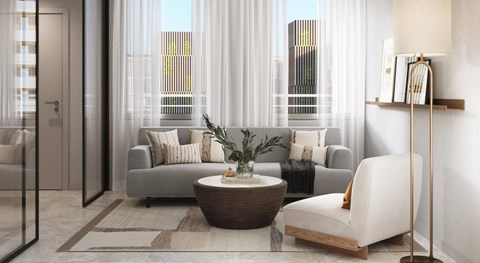 A modern living room with a grey sofa, a round wooden coffee table, and a white chair.