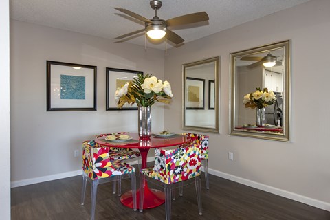 A dining room with a table set for two and a ceiling fan.