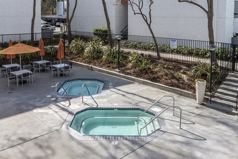 A pool area with a hot tub and chairs.