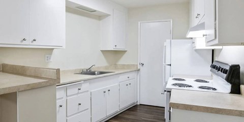 A kitchen with white cabinets and a black stove top.