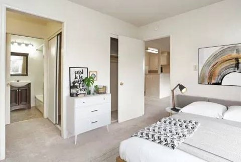 A bedroom with a white bed and a white dresser with a mirror above it.