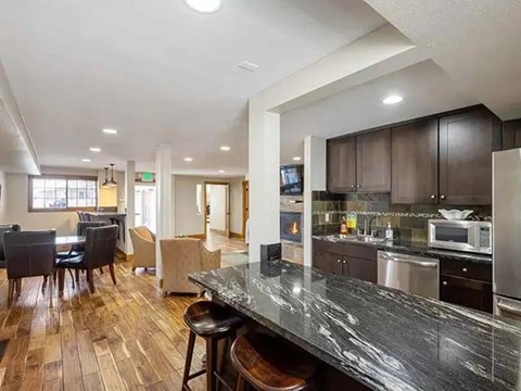 A kitchen with a black counter top and wooden floors.