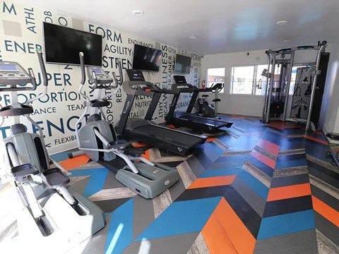 A gym with a variety of equipment including treadmills, weights, and exercise machines.